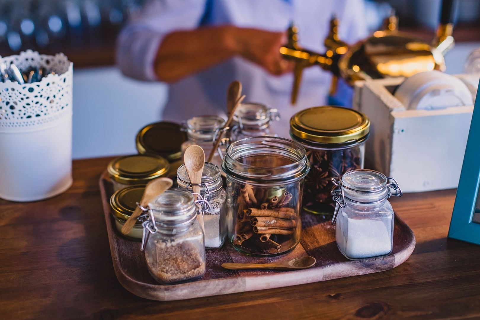 Glazen potten met kaneel, specerijen en suiker op een houten dienblad