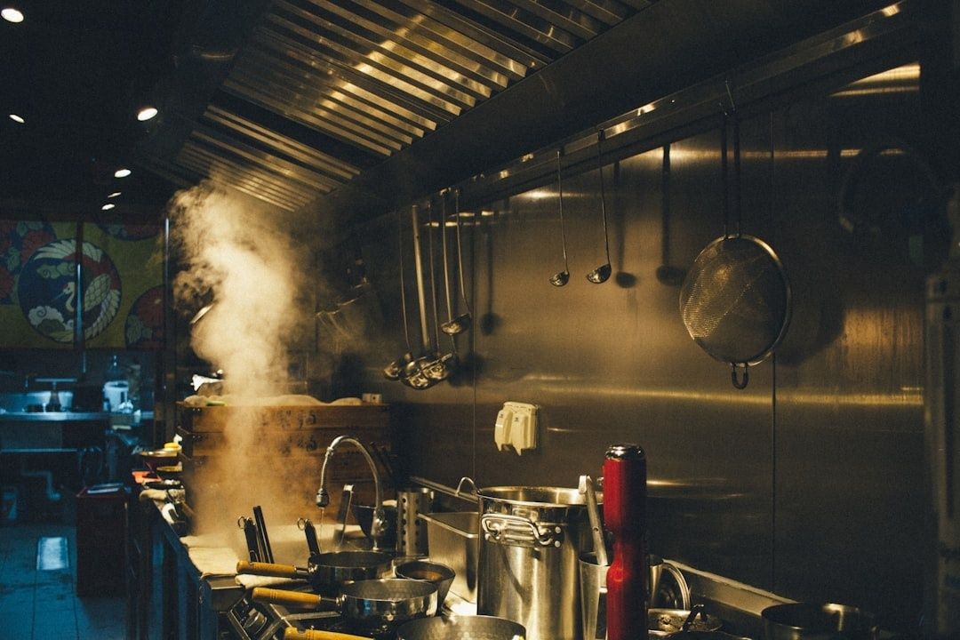 Warme restaurantkeuken met dampende pannen en opgehangen keukengerei
