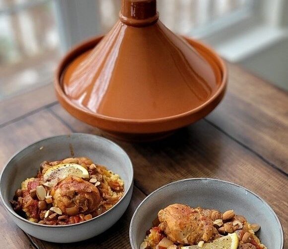 Terracotta tajine met twee kommen kruidige stoofschotel op tafel